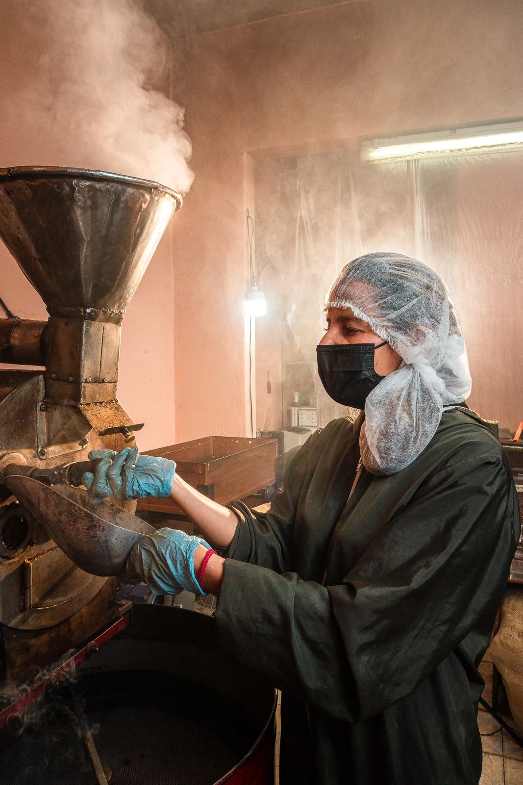 A worker operating industrial coffee-roasting equipment in a production facility