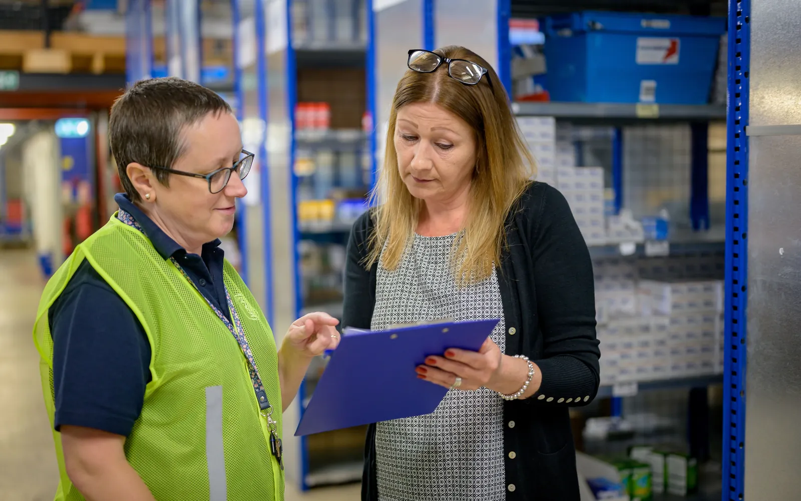 Two employees reviewing an inspection checklist beside storage shelves.