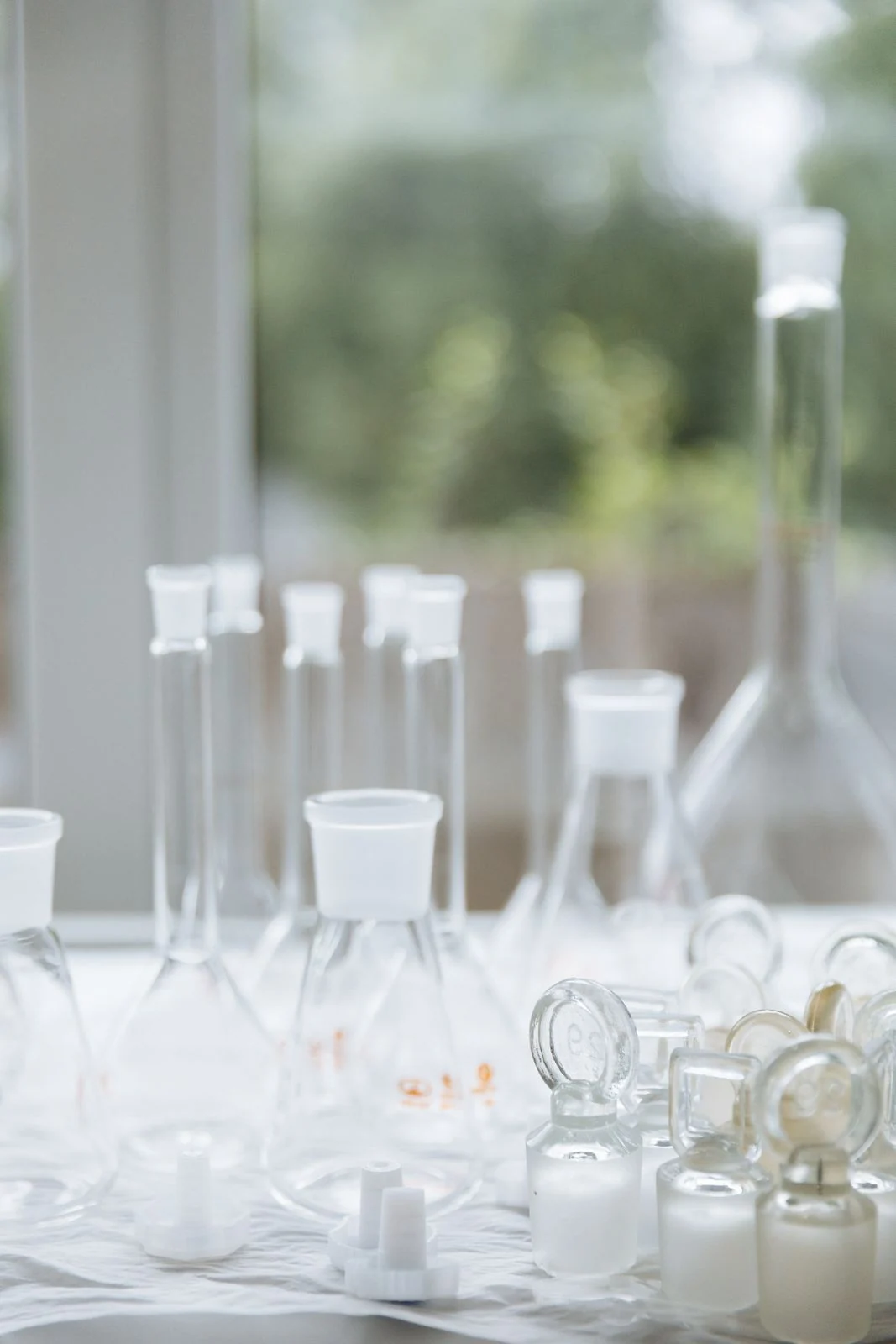 Glass laboratory bottles and analytical equipment on a bright workbench.